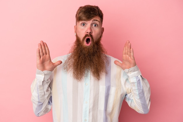 Giovane uomo caucasico dello zenzero con la barba lunga isolata su fondo rosa che ha un'idea, concetto di ispirazione.