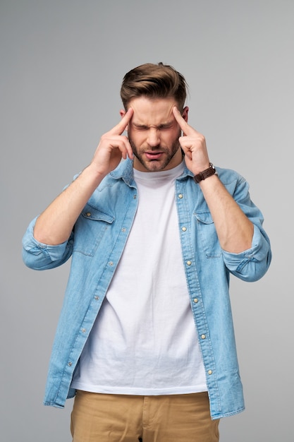 Giovane uomo caucasico frustrato in camicia di jeans che tocca la testa con la mano mentre levandosi in piedi