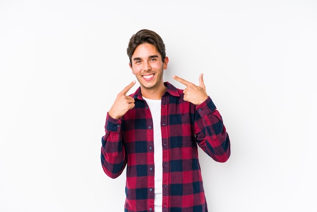 Giovane uomo caucasico in posa in un sorriso isolato rosa, puntando le dita alla bocca.