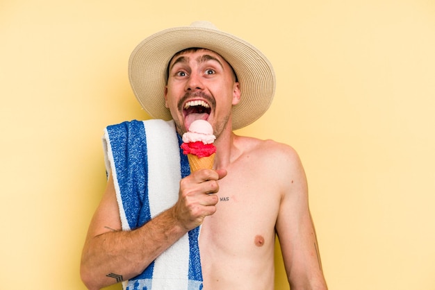 Giovane uomo caucasico in possesso di un gelato isolato su sfondo giallo