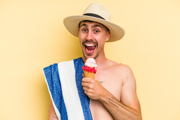 Giovane uomo caucasico in possesso di un gelato isolato su sfondo giallo