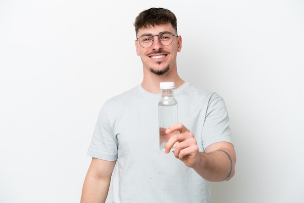 Giovane uomo caucasico in possesso di una bottiglia d'acqua isolata su sfondo bianco con felice espressione