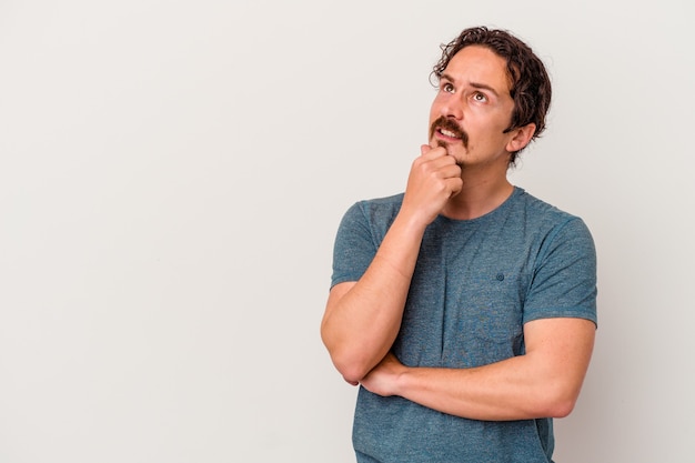 Giovane uomo caucasico isolato su bianco rilassato pensando a qualcosa guardando uno spazio di copia.