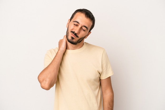 Giovane uomo caucasico isolato su sfondo bianco che ha un dolore al collo dovuto allo stress, massaggiandolo e toccandolo con la mano.