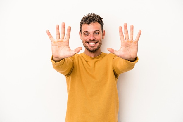 Giovane uomo caucasico isolato su sfondo bianco che mostra il numero dieci con le mani.