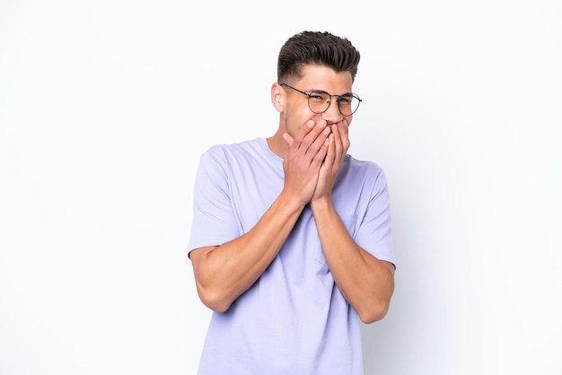 Giovane uomo caucasico isolato su sfondo bianco felice e sorridente che copre la bocca con le mani