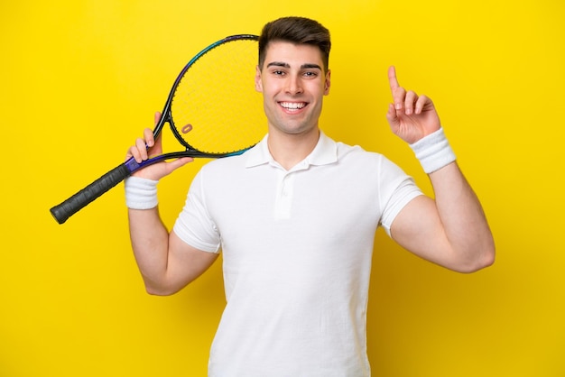 Giovane uomo caucasico isolato su sfondo bianco giocando a tennis e rivolto verso l'alto