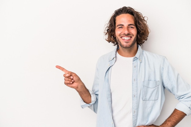 Giovane uomo caucasico isolato su sfondo bianco sorridente allegramente puntando con l'indice lontano.