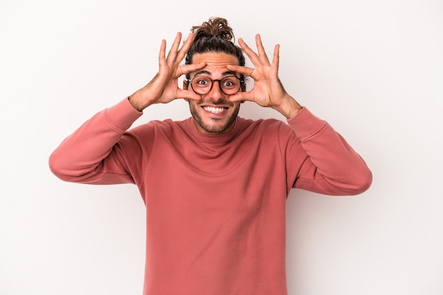 Giovane uomo caucasico isolato su sfondo bianco tenendo gli occhi aperti per trovare un'opportunità di successo.