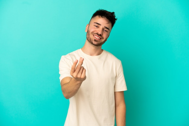 Giovane uomo caucasico isolato su sfondo blu che fa soldi gesture