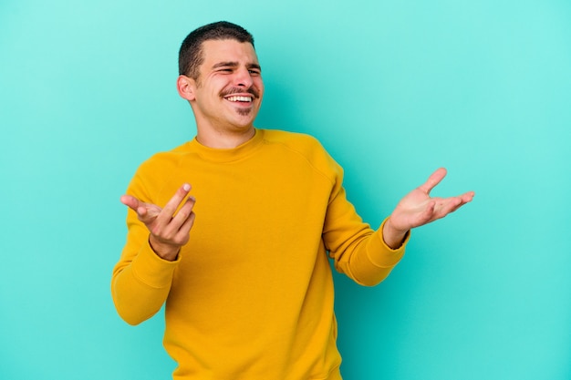 Giovane uomo caucasico isolato su sfondo blu gioioso ridendo molto. Concetto di felicità.