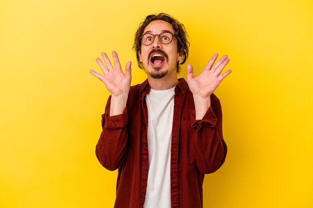 Giovane uomo caucasico isolato su sfondo giallo che grida al cielo, alzando lo sguardo, frustrato.