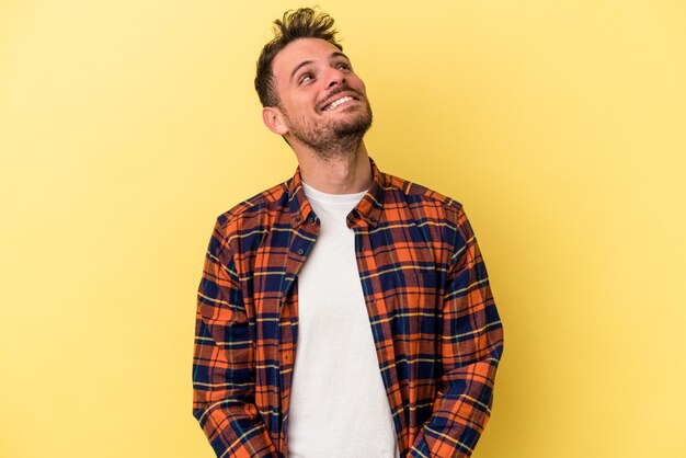 Giovane uomo caucasico isolato su sfondo giallo collo ridente rilassato e felice allungato mostrando i denti