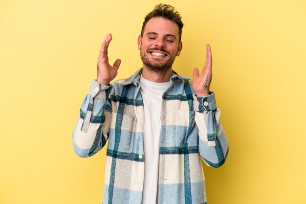 Giovane uomo caucasico isolato su sfondo giallo gioioso ridendo molto. Concetto di felicità.