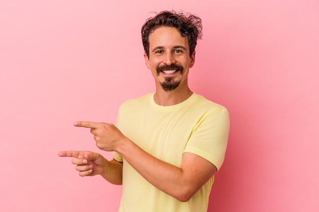 Giovane uomo caucasico isolato su sfondo rosa eccitato indicando con l'indice lontano.