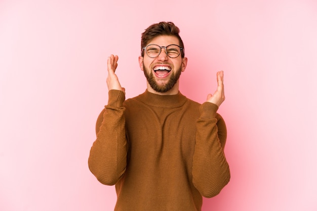 Giovane uomo caucasico isolato su spazio rosa gioioso ridendo molto. Concetto di felicità.