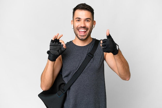 Giovane uomo caucasico sportivo con borsa sportiva su sfondo bianco isolato che mostra il segno ok e il gesto del pollice in su