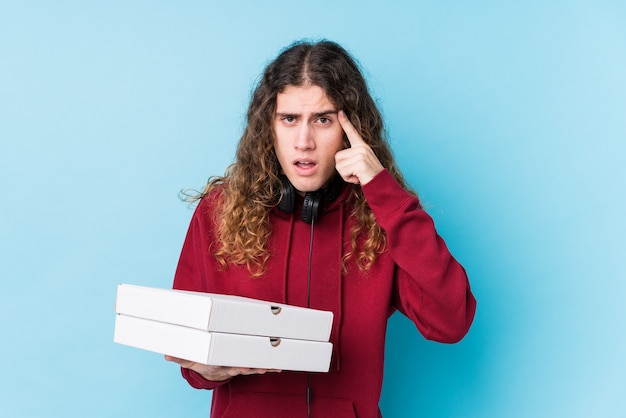 Giovane uomo caucasico tenendo le pizze isolate mostrando un gesto di delusione con l'indice.