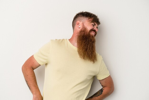 Giovane uomo caucasico zenzero con barba lunga isolato su sfondo bianco che soffre di mal di schiena.