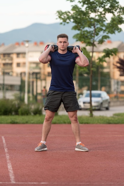 Giovane uomo che esegue esercizio di squat borsa all'aperto