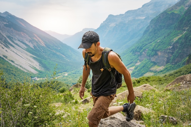 Giovane uomo che fa trekking sulla cima di una montagna verde