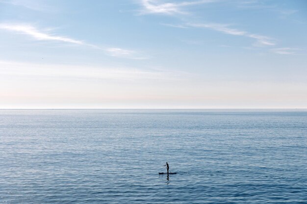 Giovane uomo che galleggia su una tavola SUP L'avventura del mare con acqua blu su un surf