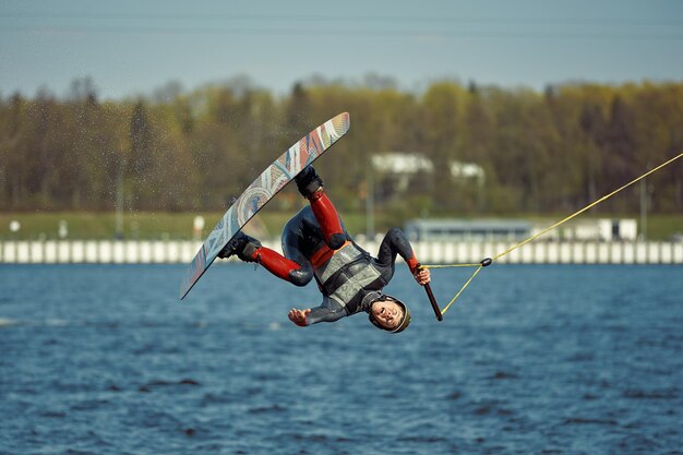 Giovane uomo che guida il wakeboard su un lago estivo.