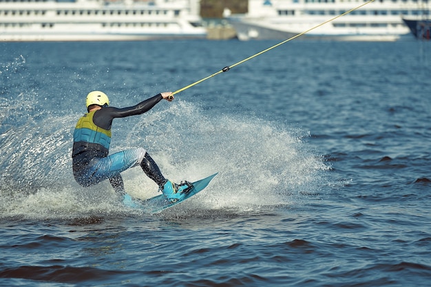 Giovane uomo che guida il wakeboard su un lago estivo.