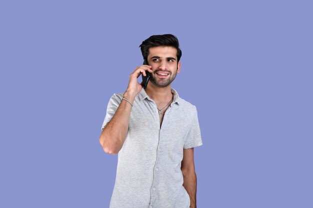 Giovane uomo che indossa abiti estivi parlando al telefono con un sorriso faccia modello pakistano indiano