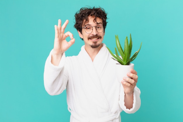 Giovane uomo che indossa accappatoio sentirsi felice, mostrando approvazione con un gesto ok