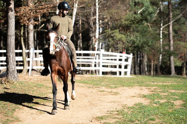 Giovane uomo che indossa casco e cavallo