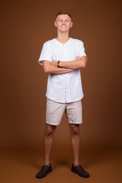 Giovane uomo che indossa una camicia bianca su sfondo marrone