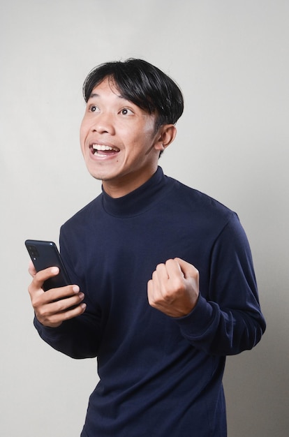 Giovane uomo che manda un sms leggendo in chat sul suo telefono sorpreso felice