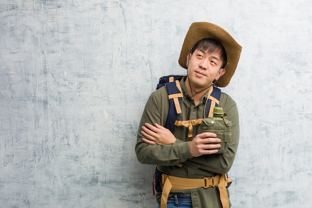 Giovane uomo cinese dell&#39;esploratore che sorride sicuro e che attraversa armi, cercando