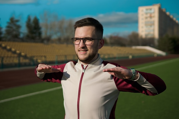 Giovane uomo con gli occhiali che si estende su uno stadio