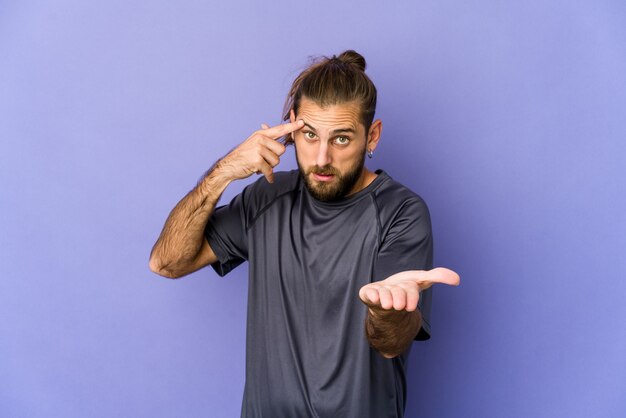 Giovane uomo con i capelli lunghi guarda tenendo e mostrando un prodotto a portata di mano.