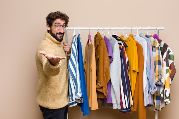 Giovane uomo con la barba fresca con vestiti contro la parete piatta