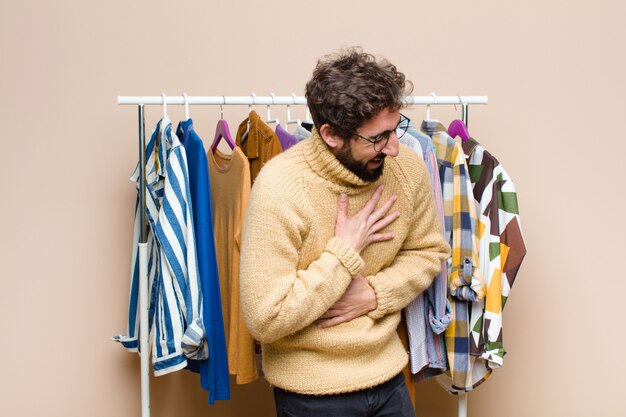 Giovane uomo con la barba fresca con vestiti contro la parete piatta