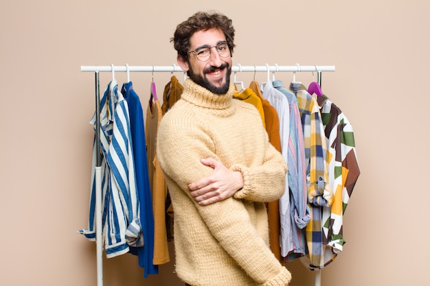 Giovane uomo con la barba fresca con vestiti contro la parete piatta