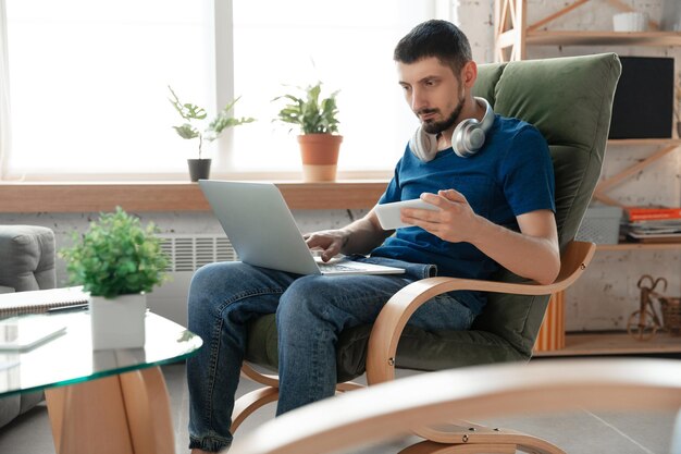 Giovane uomo concentrato che studia a casa durante i corsi online o informazioni gratuite da solo