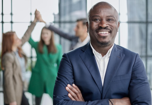 Giovane uomo d'affari africano alzando il palmo aperto sullo sfondo dei colleghi