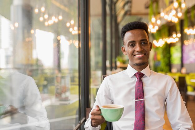 Giovane uomo d'affari africano bello nel ristorante della caffetteria