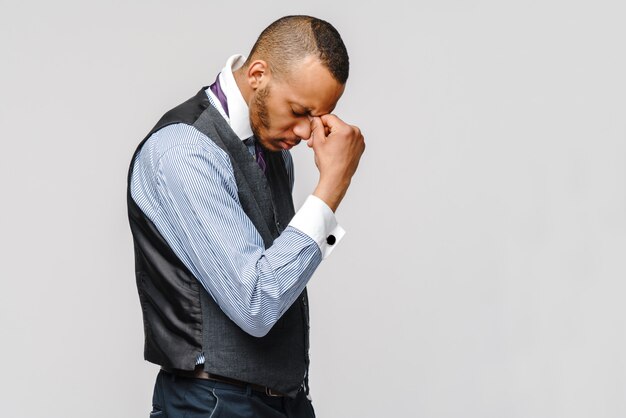 Giovane uomo d'affari afroamericano che tocca la testa a causa di mal di testa e stress