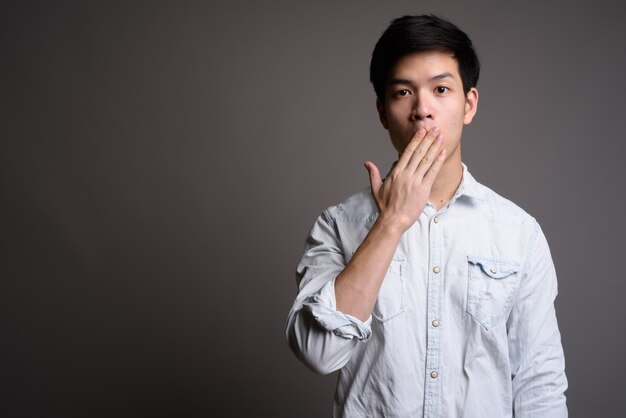 giovane uomo d'affari asiatico bello che indossa camicia bianca su grigio