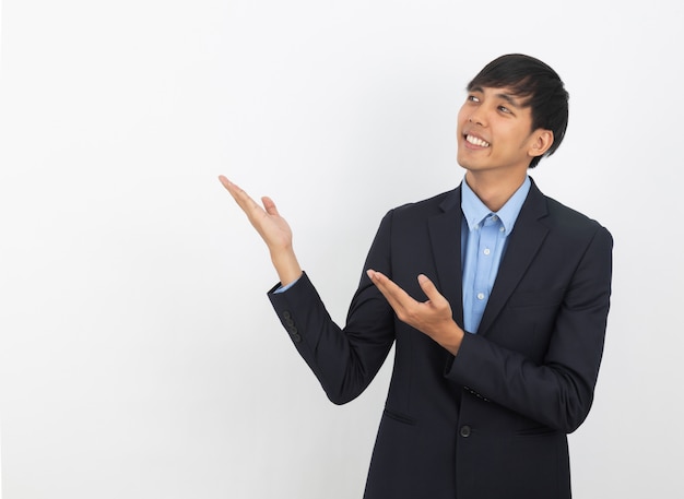 Giovane uomo d'affari asiatico con camicia blu che punta verso il lato con una mano per presentare un prodotto o un'idea