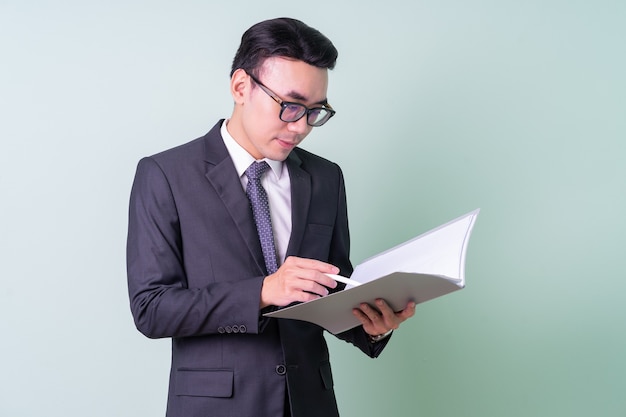 Giovane uomo d'affari asiatico in posa su sfondo verde