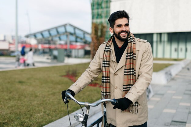 Giovane uomo d'affari bello in piedi sulla strada della città con la bicicletta. Protezione dell'ambiente e concetto di trasporto ecologico.