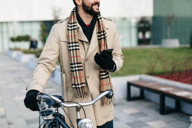 Giovane uomo d'affari bello in piedi sulla strada della città con la bicicletta. Protezione dell'ambiente e concetto di trasporto ecologico.