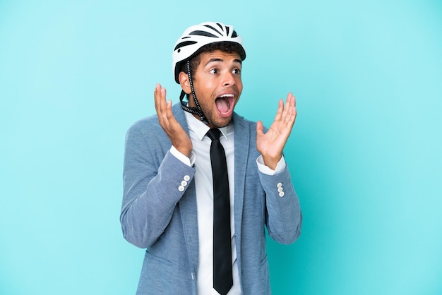 Giovane uomo d'affari brasiliano con casco da bici isolato su sfondo blu con espressione facciale a sorpresa