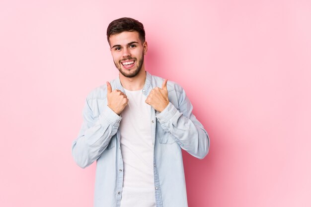 Giovane uomo d'affari caucasico in posa in un muro bianco isolato alzando entrambi i pollici in su, sorridente e fiducioso.